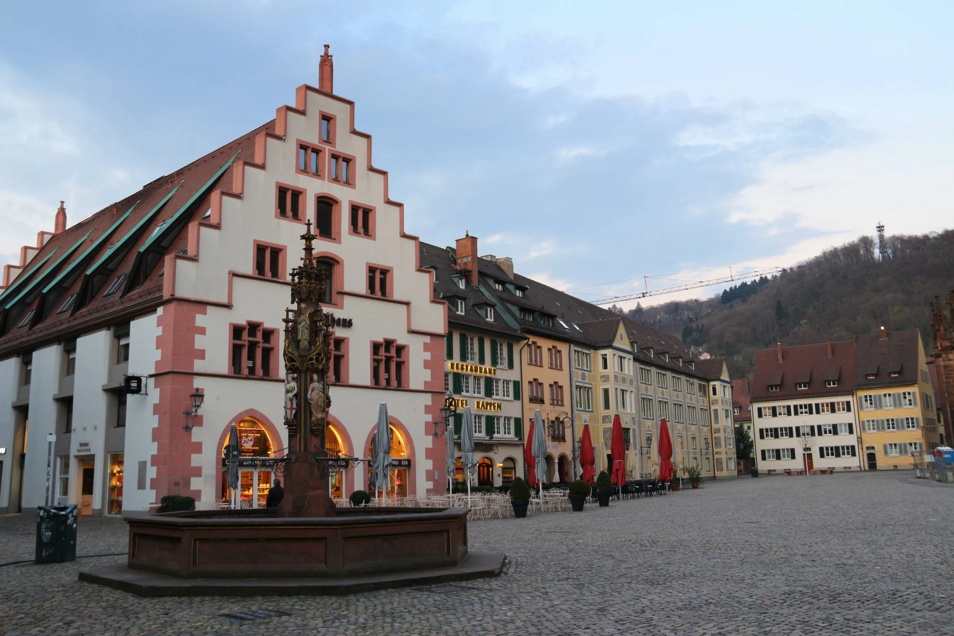 Prédios típicos da região, no caso o Café Kornhaus, e, em primeiro plano, a Fischbrunnen ou fonte de peixes. Todos Localizados na Münsterplatz